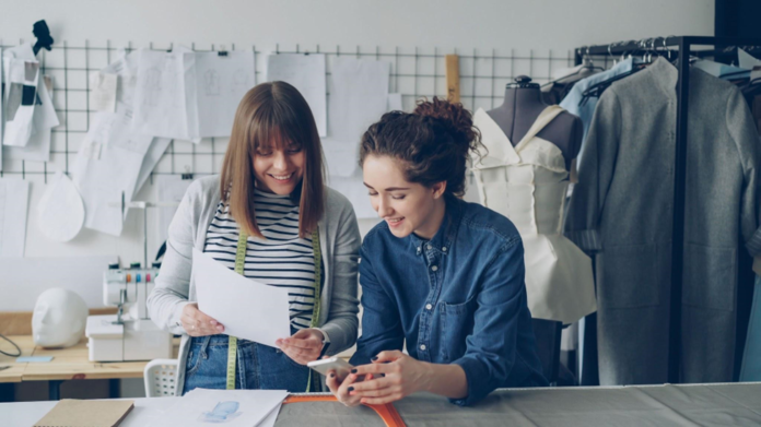 Two fashion design business owners working on a project in their workshop.