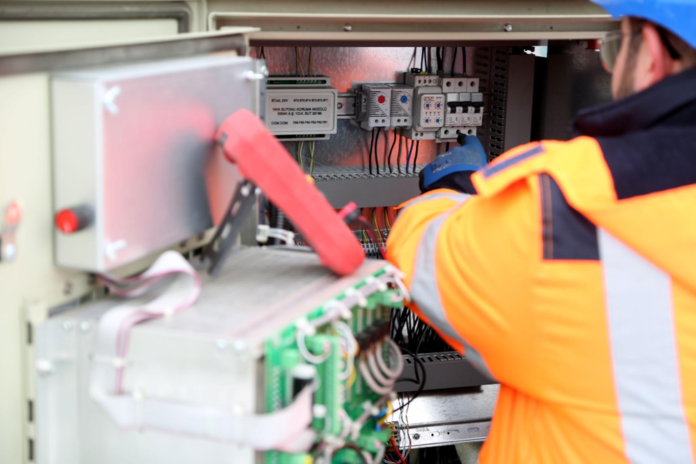 Electrician inspecting industrial electrical circuit board.
