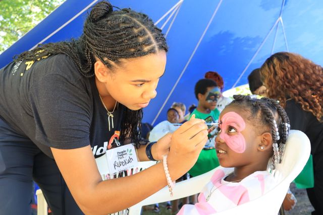 Face painting artist creating a butterfly design on a child's face at a children's event