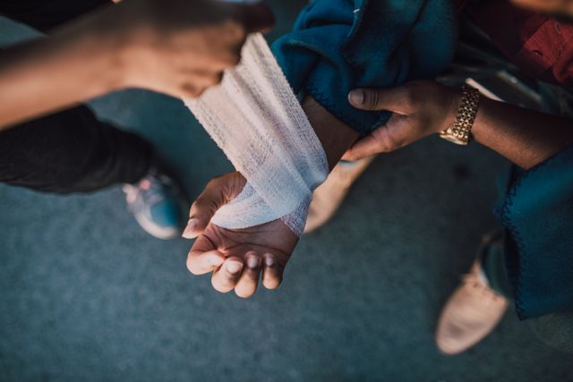 Person receiving first aid wrist bandage after auto injury treatment